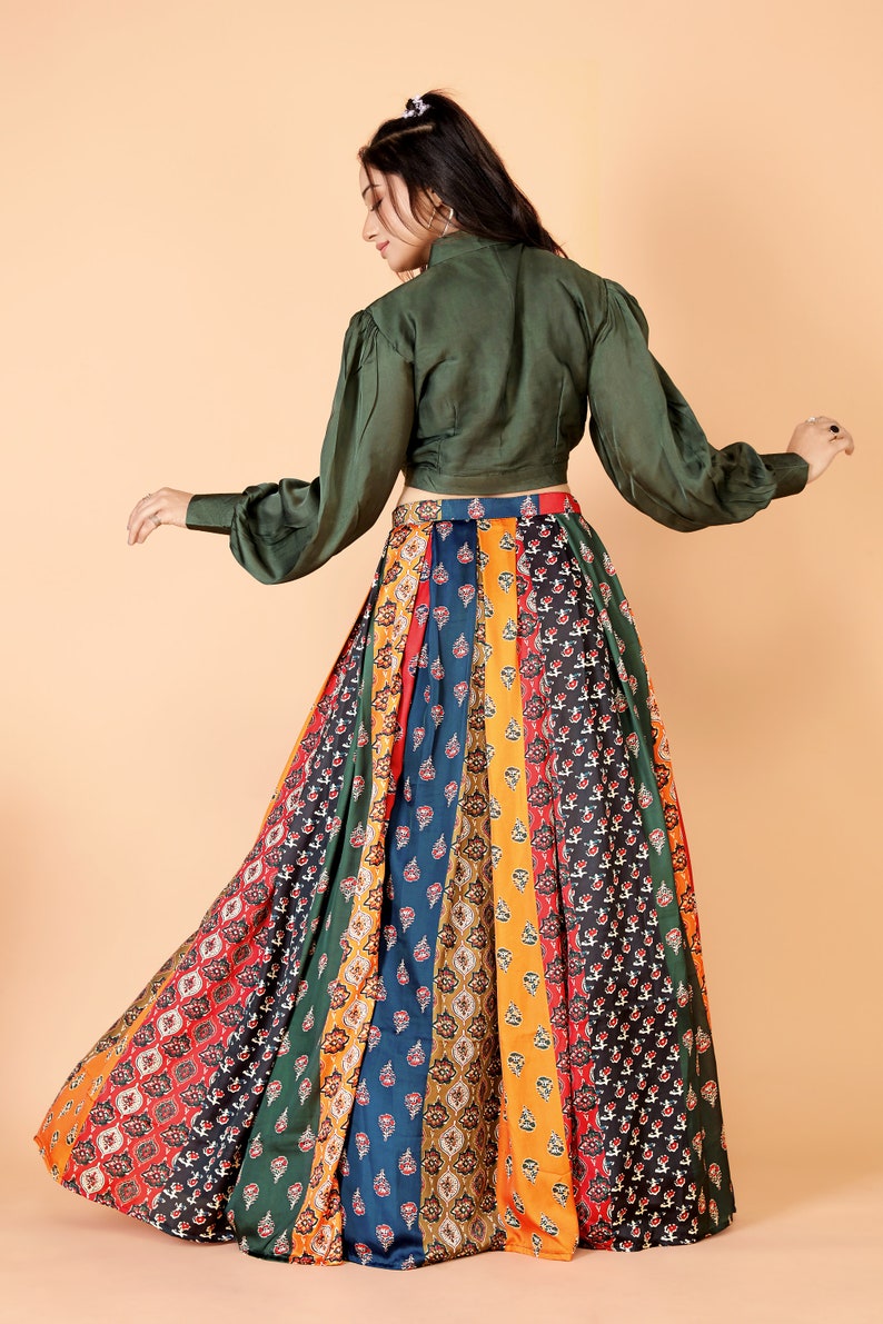 May include: A long, flowing skirt with a patchwork design in various colors, including red, orange, green, and blue. The skirt is paired with a dark green long-sleeved top. The outfit is suitable for a variety of occasions.
