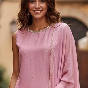 May include: A sleeveless, dusty rose-colored outfit with delicate floral embroidery. The ensemble includes a top with a beaded neckline and a matching draped shawl. The outfit is made of a soft, flowing fabric, perfect for a special occasion.