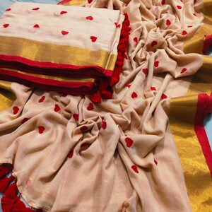 May include: A beige fabric with red heart embroidery, gold trim, and red tassels. The fabric is folded and draped, with a folded stack of the same fabric on the left. The image includes the text "vivo V40 | ZEISS" and the date and time.