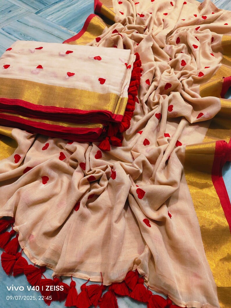 May include: A beige fabric with red heart embroidery, gold trim, and red tassels. The fabric is folded and draped, with a folded stack of the same fabric on the left. The image includes the text "vivo V40 | ZEISS" and the date and time.