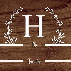 May include: White silhouette of a leafy wreath with the letter H in the center. The text "The Family" is below the wreath.