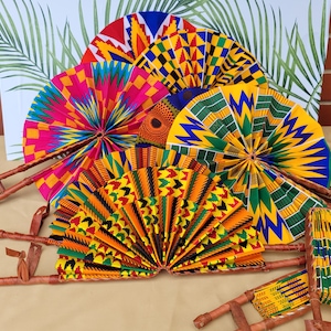 May include: A set of six colourful hand fans with wooden handles. The fans are made of fabric with a traditional African print in yellow, red, green, and black.