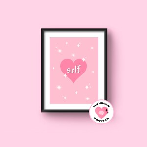 May include: Pink and white print with a pink heart and the word "self" in a gothic font. The print is framed in a black frame. The print is from The Urban Ponytail.