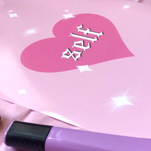 May include: Pink poster with a pink heart and the word "Self" in white gothic lettering. The background has white glitter stars.