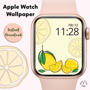 May include: A pink Apple Watch with a lemon-themed wallpaper. The watch face displays the time as 11:28 and the day as FRI 12. The wallpaper features lemons, lemon slices, and green leaves on a light yellow background.