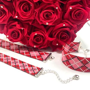 May include: Three beaded bracelets and a bouquet of red roses. The bracelets feature a red, pink, and white argyle pattern with silver-toned clasps. The roses have small, sparkling embellishments.
