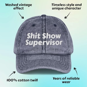 May include: A blue baseball cap with the text "Shit Show Supervisor" in white. The cap has a washed vintage effect and is made of 100% cotton twill. It is designed for years of reliable wear.