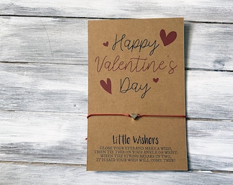 以下が含まれることがあります： 「Happy Valentine's Day」と書かれた茶色のカードに、小さなハートのチャームが付いた赤い紐が結ばれています。カードには「Little Wishers」という文字と、願い事を叶える方法が書かれています。
