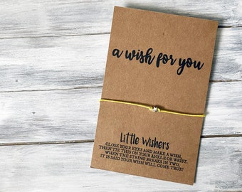 May include: A brown card with the text "a wish for you" and "Little Wishers" printed on it. The card is tied with a yellow string and a silver star charm.