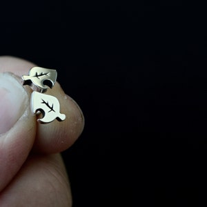 May include: A pair of silver leaf-shaped earrings. The earrings are small and delicate, and they have a simple design.