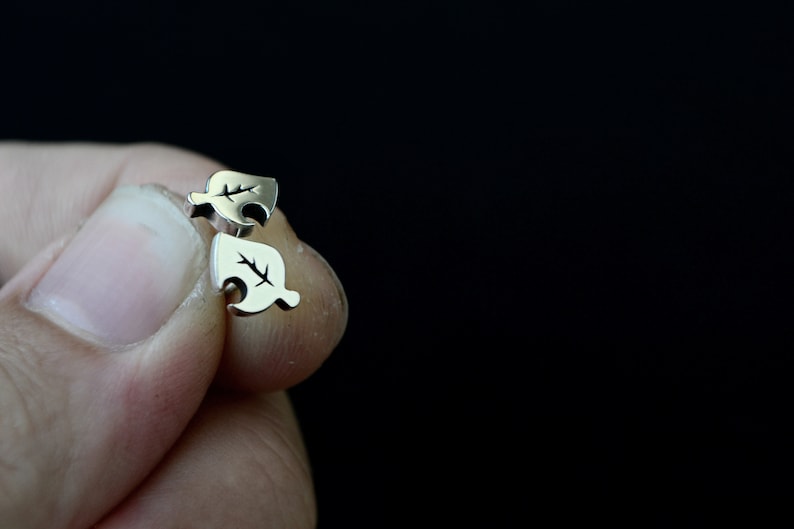 May include: A pair of silver leaf-shaped earrings. The earrings are small and delicate, and they have a simple design.
