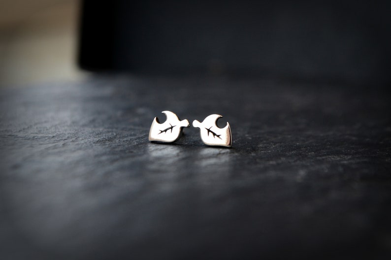 May include: A pair of silver earrings with a leaf design. The earrings are small and delicate.