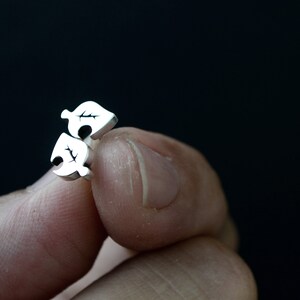 May include: A pair of silver earrings with a leaf design. The earrings are small and delicate.