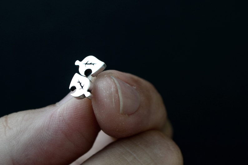 May include: A pair of silver earrings with a leaf design. The earrings are small and delicate.