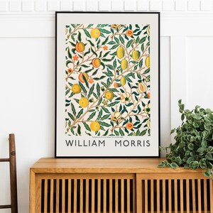 Puede incluir: Una impresi&oacute;n enmarcada de una ilustraci&oacute;n bot&aacute;nica vintage que presenta un patr&oacute;n repetitivo de hojas verdes, frutos naranjas y flores blancas. La impresi&oacute;n est&aacute; titulada "William Morris".
