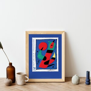 May include: A framed print of a colorful abstract painting on a blue background. The painting features a red, green, and black abstract figure with a yellow beak. The text "REPUBLIQUE FRANCAISE" and "200" are visible on the print.