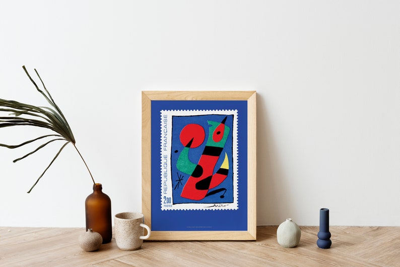 May include: A framed print of a colorful abstract painting on a blue background. The painting features a red, green, and black abstract figure with a yellow beak. The text "REPUBLIQUE FRANCAISE" and "200" are visible on the print.