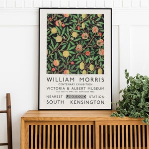 May include: A black and white poster with a floral design in shades of pink, yellow, and green. The poster advertises a William Morris Centenary Exhibition at the Victoria & Albert Museum in London, England. The exhibition ran from February 10th to April 8th and admission was free. The nearest Underground station is South Kensington.