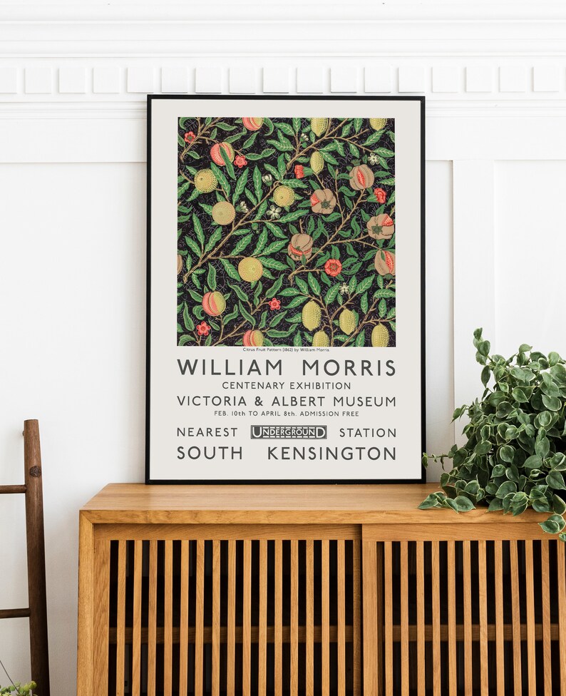 May include: A black and white poster with a floral design in shades of pink, yellow, and green. The poster advertises a William Morris Centenary Exhibition at the Victoria & Albert Museum in London, England. The exhibition ran from February 10th to April 8th and admission was free. The nearest Underground station is South Kensington.