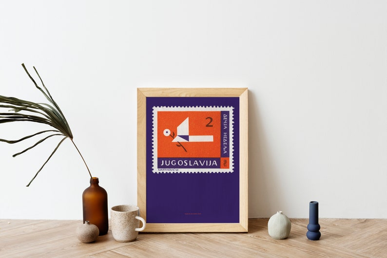 May include: A framed print of a vintage postage stamp from Yugoslavia. The stamp features a stylized orange bird with a white flower and the text "JUGOSLAVIJA" and "2 DINARA NEDELJA".