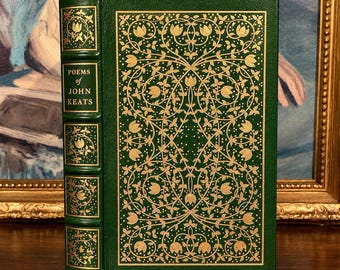 May include: A green hardcover book titled Poems of John Keats with gold foil floral patterns on the front cover and spine. The spine features raised bands and decorative gold leaf detailing, while the front cover displays a symmetrical vine design.