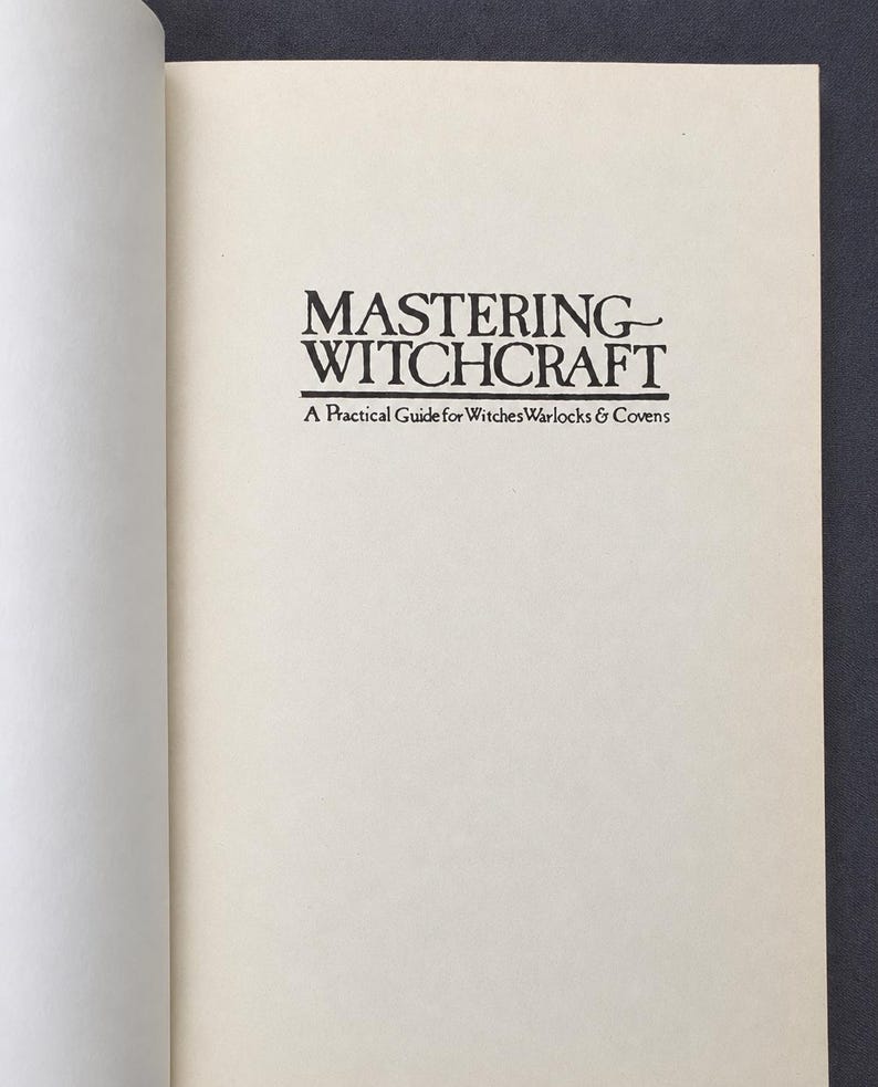 Puede incluir: P&aacute;gina de un libro abierto con el t&iacute;tulo "MASTERING WITCHCRAFT" en negro, con una fuente estilizada. Debajo, el subt&iacute;tulo dice "A Practical Guide for Witches, Warlocks & Covens". Las p&aacute;ginas son de color crema.