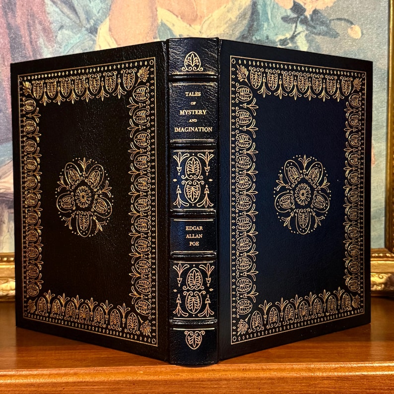 Vintage Leather-bound edition of “Tales of Mystery and Imagination” by Edgar Allan Poe with ornate gold detailing on the spine and cover. The book is displayed upright on a shelf.