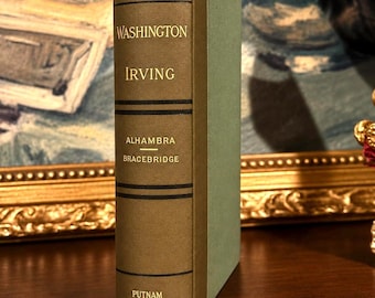 May include: A hardcover book with a tan spine and light green covers. The spine features black horizontal lines and gold text reading WASHINGTON, IRVING, ALHAMBRA, BRACEBRIDGE, and PUTNAM. The book is standing upright on its bottom edge.