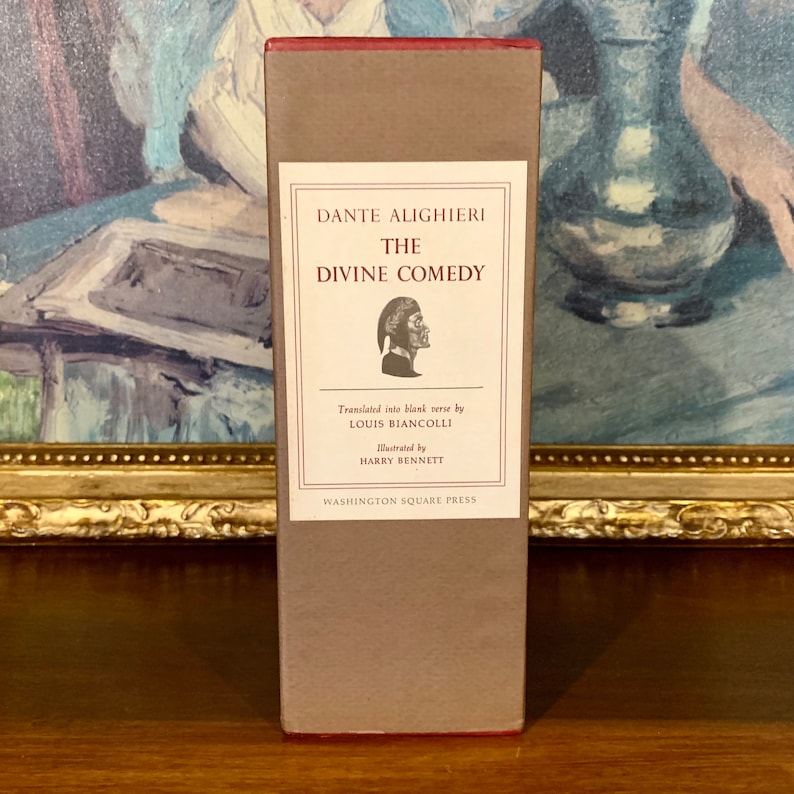 May include: A brown book titled "The Divine Comedy" by Dante Alighieri. The book is translated by Louis Biancolli and illustrated by Harry Bennett. It is published by Washington Square Press.