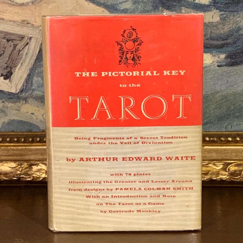 May include: A vintage book titled "THE PICTORIAL KEY to the TAROT" with a red and cream cover. The book features text by Arthur Edward Waite and illustrations by Pamela Colman Smith. The cover has an illustration of a woman.