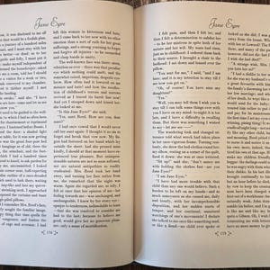 Peut inclure: Un livre ouvert &agrave; couverture rigide affichant deux pages de texte du roman Jane Eyre. Les pages sont num&eacute;rot&eacute;es 174 et 175 en bas, avec un texte imprim&eacute; en noir sur papier blanc cass&eacute;, une police &agrave; empattement et de larges marges.