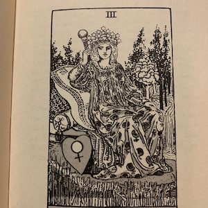 May include: Black and white illustration of The Empress tarot card. The card features a woman wearing a crown and holding a scepter, seated on a throne. The card has the number III at the top and the words "THE EMPRESS" at the bottom.