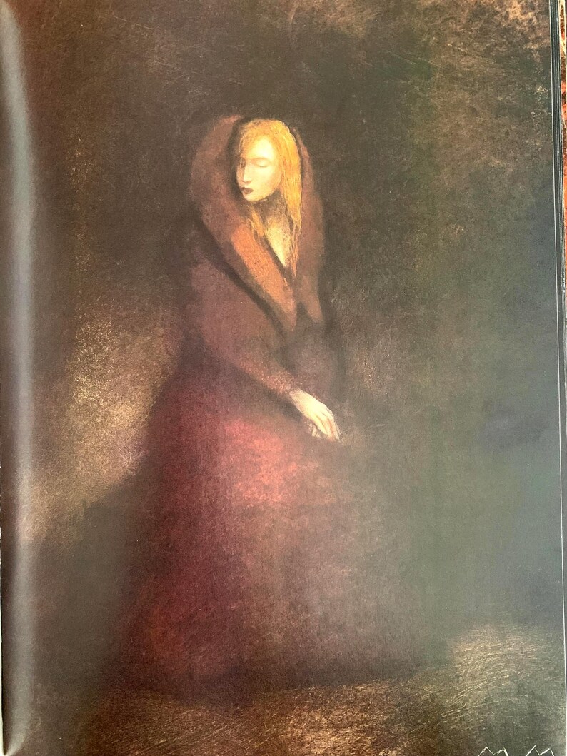 May include: A woman in a long, burgundy dress with a fur-trimmed hood sits in a dimly lit room. Her blonde hair is visible beneath the hood, and she has a soft, contemplative expression on her face.