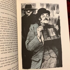 May include: A black and white illustration of a man holding a small, rectangular object. The man is wearing a suit and a hat. He has a mustache and a surprised expression on his face. The background is dark and shadowy.