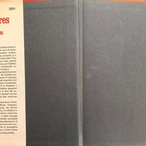 May include: The cover of "The Book of Vampires" by Dudley Wright. The title and author's name are in red text on a white background. The book's spine is dark gray, and the pages contain text about vampires.