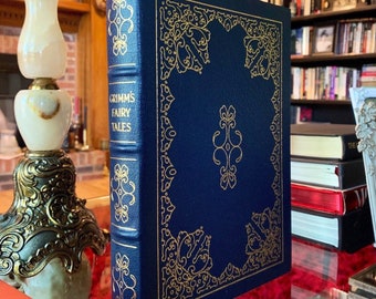 May include: A navy blue hardcover book with gold lettering and decorative accents. The title of the book is "Grimm's Fairy Tales".