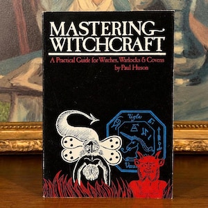 Puede incluir: Un libro antiguo titulado "Mastering Witchcraft" con una portada negra. La portada presenta ilustraciones en blanco y rojo de figuras y s&iacute;mbolos m&iacute;sticos. Tambi&eacute;n es visible el nombre del autor, Paul Huson.