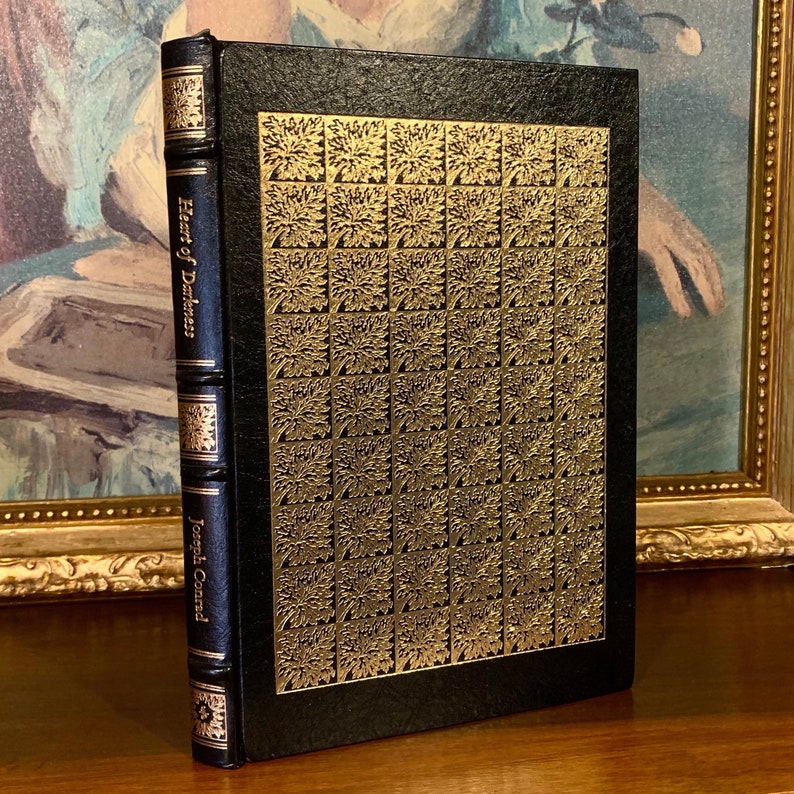 Easton Press Heart of Darkness by Joseph Conrad, 1980 edition. Black leather-bound book with ornate 22k gold gilt design and hubbed spine. A collectible vintage classic for fine home libraries and literary collectors.