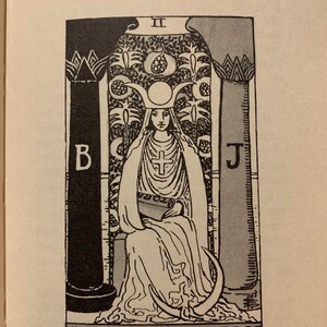 May include: Black and white illustration of The High Priestess tarot card. The image features a woman in a long white robe, seated between two pillars. The text "The Doctrine Behind the Veil 77" is at the top.