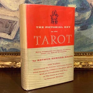 May include: A vintage book titled "THE PICTORIAL KEY to the TAROT" with a red and cream cover. The book features text by Arthur Edward Waite and illustrations by Pamela Colman Smith. The book is a guide to tarot divination.