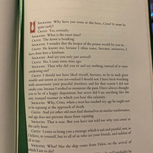May include: A close-up of a page from a book with text about the Greek philosopher Socrates. The text discusses Socrates's death and the arrival of a ship from Delos.