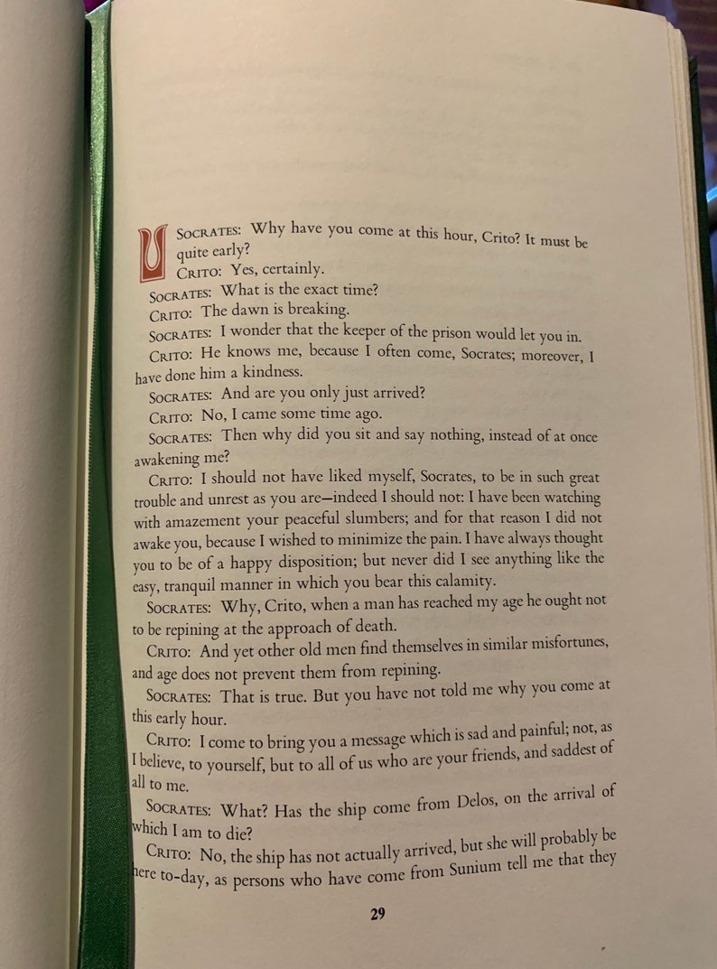 May include: A close-up of a page from a book with text about the Greek philosopher Socrates. The text discusses Socrates's death and the arrival of a ship from Delos.