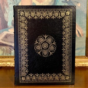 Vintage Leather-bound edition of “Tales of Mystery and Imagination” by Edgar Allan Poe with ornate gold detailing on the cover. The book is displayed upright on a shelf.
