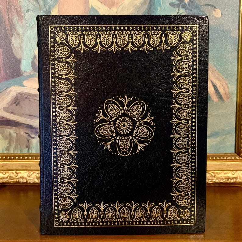 Vintage Leather-bound edition of “Tales of Mystery and Imagination” by Edgar Allan Poe with ornate gold detailing on the cover. The book is displayed upright on a shelf.