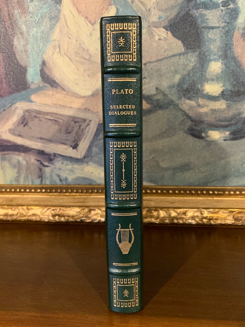 May include: A dark green hardcover book with gold lettering and a gold lyre design on the spine. The title of the book is "PLATO SELECTED DIALOGUES".