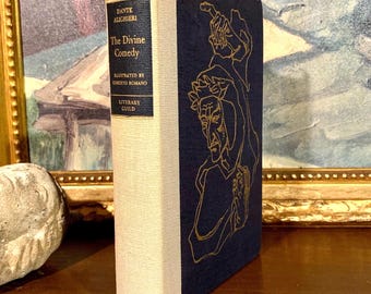 May include: A navy blue hardcover book with a gold spine and gold lettering. The book is titled "The Divine Comedy" by Dante Alighieri. The cover features a gold illustration of a man with a crown of thorns.