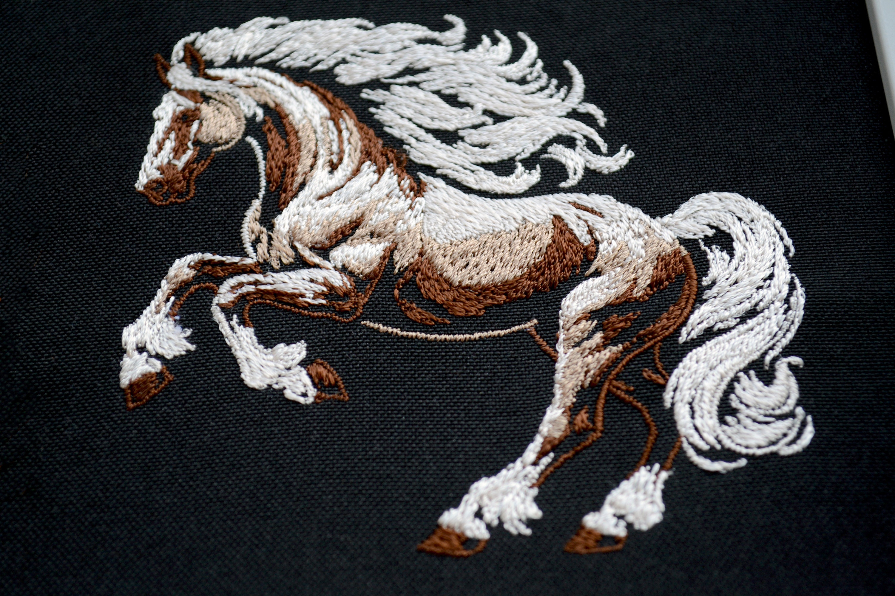 高貴な馬の刺繍デザイン - 濃い色の生地に白いたてがみを持つ野生の