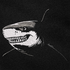 Peut inclure: Écusson brodé représentant une tête de requin stylisée en noir et blanc. Les dents et les détails du visage du requin sont blancs sur un fond noir. Le requin affiche un sourire menaçant.