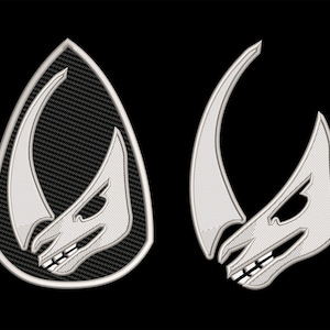 May include: Two silver embroidered patches depicting a stylised horned creature with a menacing expression. The patches are on a black background.