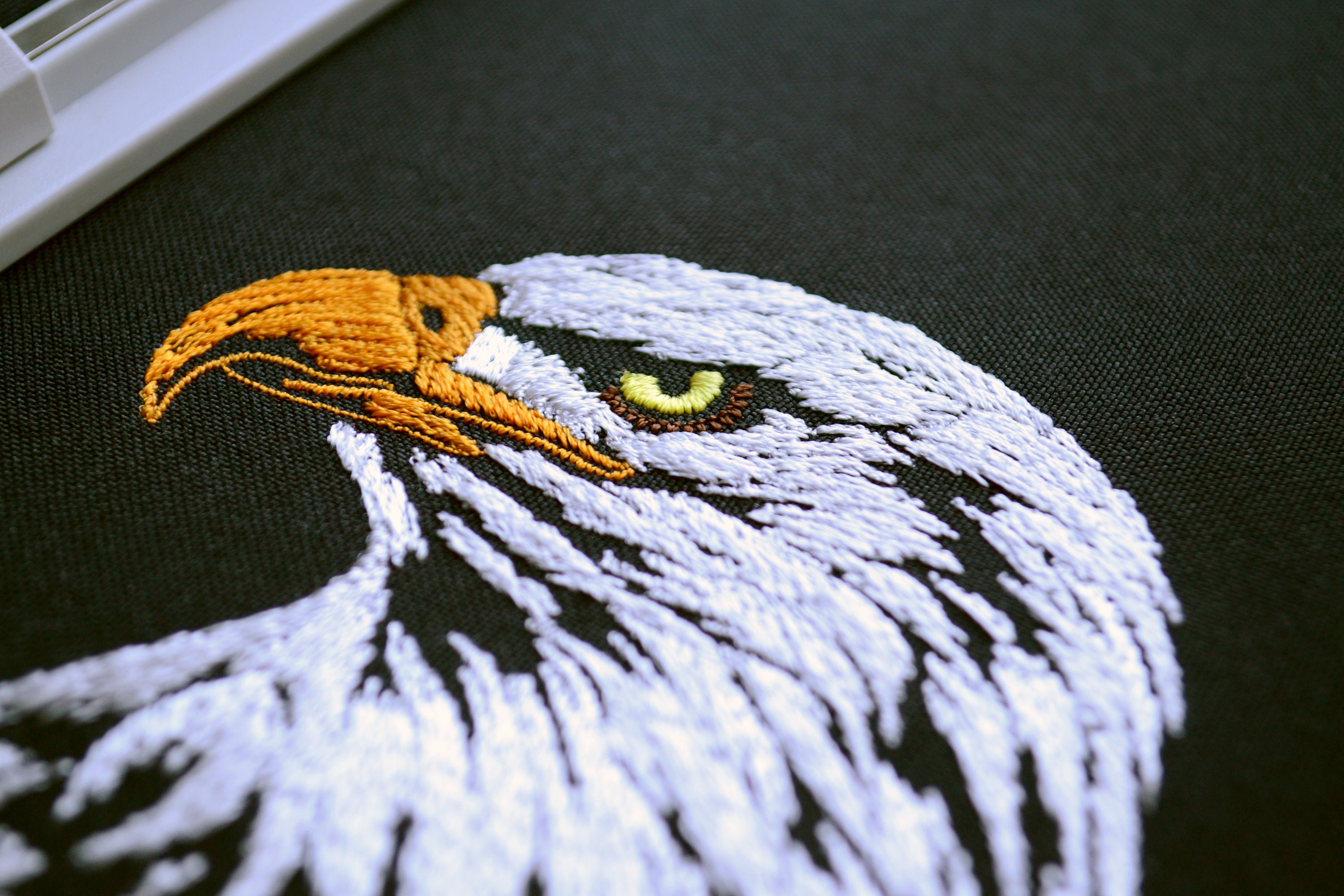 リアルな鷲の頭の刺繍デザイン - 雄大なアメリカの鳥、暗い色の生地の 